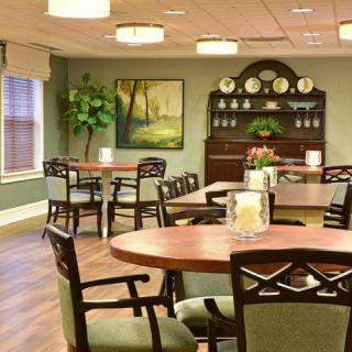A cozy dining area with neatly arranged tables and chairs, warm lighting, and elegant decor.