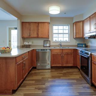 A modern kitchen featuring wooden cabinets, stainless steel appliances, and natural lighting.