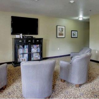 A cozy lounge area featuring several chairs, a television mounted on the wall, and a cabinet below it.