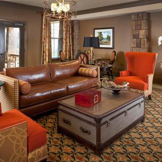 A cozy living room with a leather sofa, colorful armchairs, and a decorative coffee table.