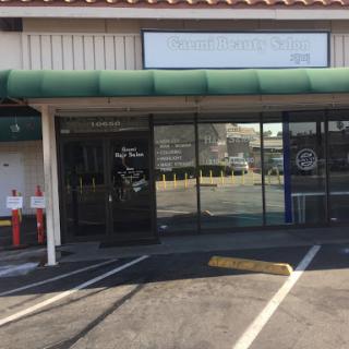 A view of a storefront with glass doors and a green awning, featuring empty parking spaces.