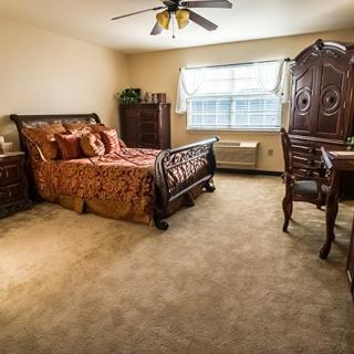 A spacious bedroom with ornate furniture, including a bed, armoire, and desk.