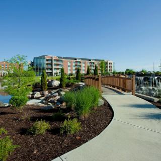 A scenic outdoor view featuring a modern residential building surrounded by landscaped greenery and a winding pathway.