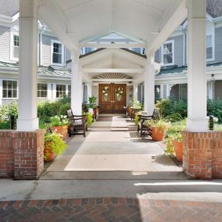 A welcoming entrance with columns and potted plants leading to a building.