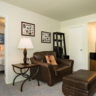 A cozy living room featuring a leather armchair, ottoman, and a decorative table lamp.