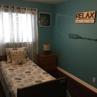 A cozy bedroom with blue walls, featuring a single bed and decorative elements.