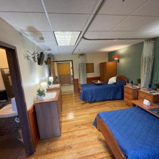 A cozy interior room featuring two beds with blue bedding, wooden furniture, and a warm atmosphere.