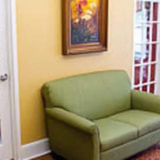 A cozy living room corner featuring a green sofa and a framed painting on the wall.