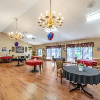 A spacious dining area featuring elegant chandeliers and a mix of round tables, ready for gatherings.