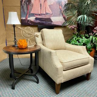 A cozy living room setup featuring a chic armchair, a stylish side table with a decorative item, and greenery for a fresh touch.
