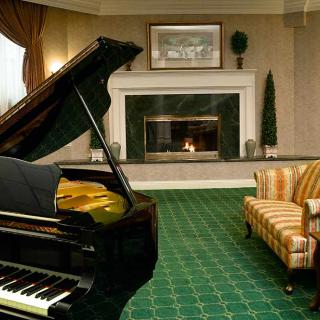 A cozy living room featuring a grand piano and a fireplace.