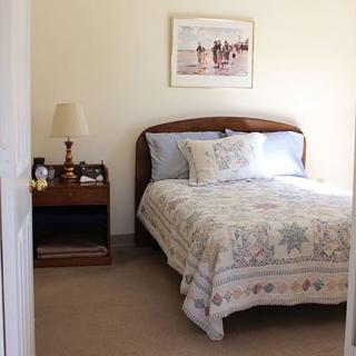 A cozy bedroom with a single bed, nightstand, and lamp.