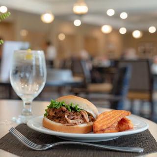 Pulled pork sandwich with sweet potato fries served in a restaurant setting.