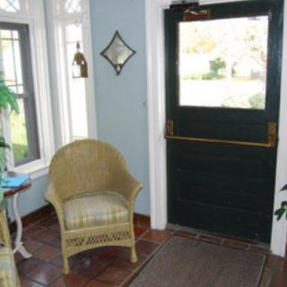 A cozy entryway with rattan chair and large windows.