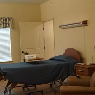 An empty hospital room with a bed and comfortable chair.