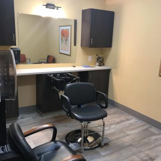 A cozy salon interior with a styling chair facing a large mirror.