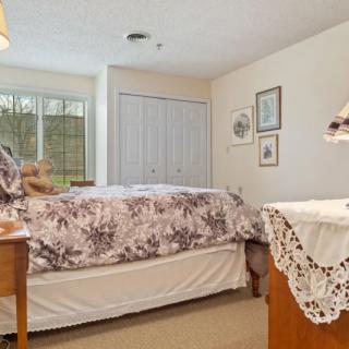 A cozy bedroom with a neatly made bed, decorative furnishings, and ample natural light from the window.