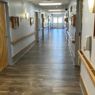 A long corridor in a healthcare facility with wooden flooring and handrails along the walls.