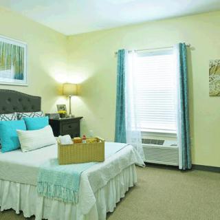 A cozy and well-decorated bedroom with a comfortable bed, bedside table, lamp, and window with curtains.