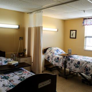 A shared patient room in a healthcare facility, featuring two beds with floral bedding.