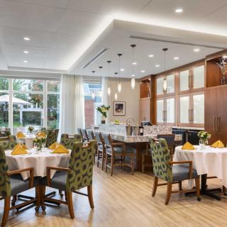An elegant restaurant dining area with neatly arranged tables and chairs, illuminated by warm lighting.