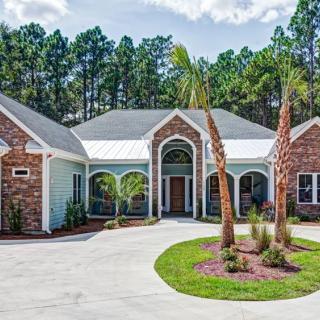 A beautiful brick house with a spacious driveway and landscaped front yard.