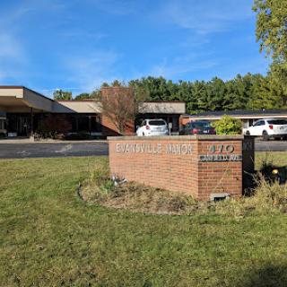 A brick sign in front of a building with a clear blue sky above.