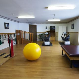 A rehabilitation center with various exercise equipment and a large yellow therapy ball.