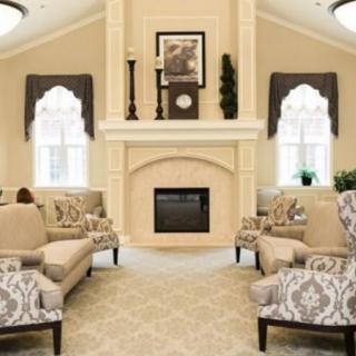 An elegantly designed living room featuring a central fireplace, patterned seating, and large windows with draped curtains.