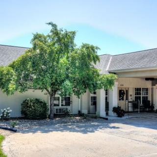 A building with a tree in front and a driveway leading to its entrance.