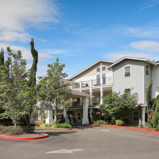 A residential building surrounded by trees under a blue sky.