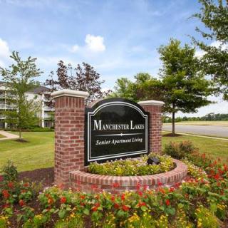 Entrance sign for an apartment complex with landscaping and flowers.