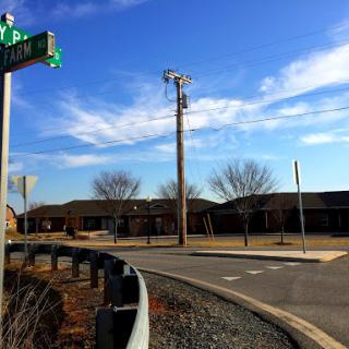 A quiet intersection with a clear blue sky and nearby buildings.