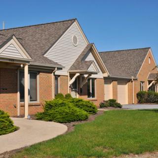 A row of suburban houses with well-maintained lawns and driveways.