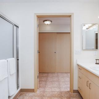 A modern bathroom featuring a glass shower, mirrored vanity, and tile flooring.