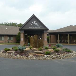 The entrance of a building with landscaped surroundings and a circular driveway.