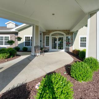 A neatly landscaped building entrance with a covered walkway and well-maintained shrubs.