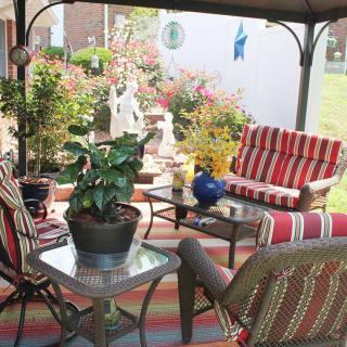A cozy patio with striped outdoor furniture and lush garden plants.