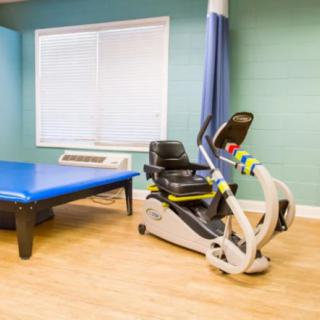 A therapy room equipped with medical exercise equipment and a treatment table.