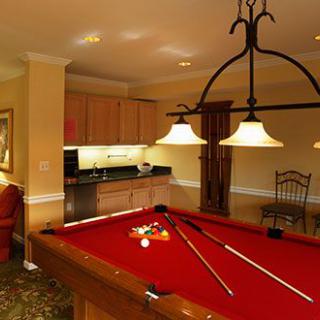 A cozy billiard room with a red pool table and warm ambient lighting.