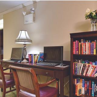 A cozy office space with desks and computers, flanked by a bookshelf filled with books.