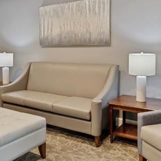 A cozy living room setup with a beige sofa, matching armchairs, and wooden coffee tables adorned with lamps.