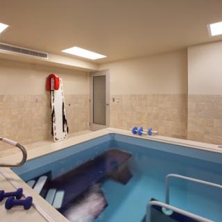 A serene indoor spa pool area featuring exercise equipment and a relaxing environment.
