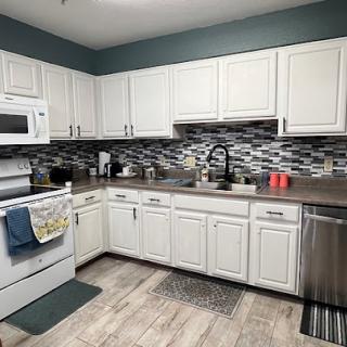 A modern kitchen with white cabinets, stylish tiles, and essential appliances.
