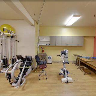 A rehabilitation room equipped with exercise machines and therapy tables.