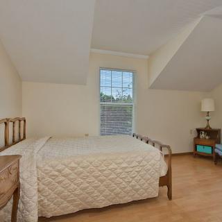 A cozy bedroom with a wooden bed, nightstand, and a large window.