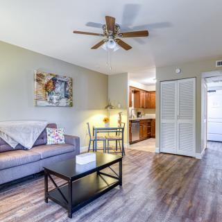 A cozy living room with a sofa, coffee table, and ceiling fan, featuring an adjacent kitchen area.