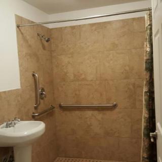 A modern bathroom with a tiled shower area and safety grab bars.