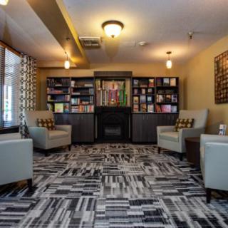 A cozy library interior featuring bookshelves, comfortable armchairs, and warm lighting.