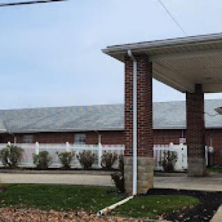 A brick building with a covered entrance and landscaped area.